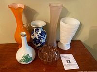 Front view of six vases arranged on wooden surface