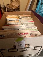 Overview of cardboard file box packed with sewing pattern envelopes showing brand tabs