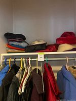 Coats and jackets hanging, hats on shelf, shoes on floor
