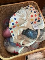 Wicker basket containing tote bag, pink and dark yarn skeins