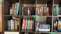 Several shelves filled with colourful children’s books, reference books, and tray of clear jewel cases