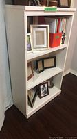 Front angled view of white three-shelf bookcase