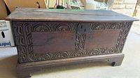 Front view of carved wood chest with iron lock plate