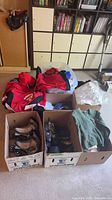 Overview showing four boxes/totes with clothing, linens and two pairs inline skates