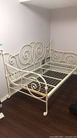 Full view of painted metal daybed frame against wall