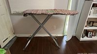 Full view of folding metal ironing board standing