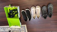 Row of five pairs of shoes including sandals, slip-ons, white Nike, grey sneakers