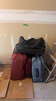 Group shot of the three suitcases and two duffel bags against wall