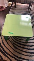 Full view of square green laminate table on rug