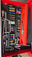 Drawer with color-coded impact sockets, torque wrench in orange case, breaker bar, lug wrench, loose chrome sockets