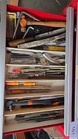 Drawer containing assortment of files, hammer, brushes, saw frame