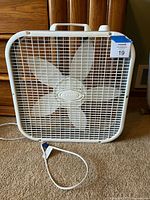 Front view of white Lasko box fan with grille and blades visible
