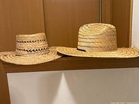 Two straw sun hats side by side on shelf