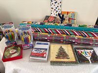 All items laid out: wrapping paper rolls, candles, labels, napkins, coasters