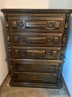 Front view of tall wood dresser showing five drawers and hardware