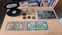 Overview of all coins, cent set, proof dollar case and both banknotes on tabletop