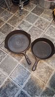 Both cast iron frying pans side by side showing relative sizes and condition