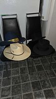 All four hats on chairs: navy cowboy, cream cowboy, two black fedoras