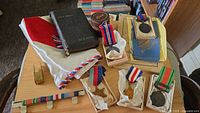 Group shot showing all medals, pamphlets, clicker, Bible, cloth, ribbon bar and case