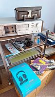 Sony TC-K55II deck on shelf with cassette case, cables, headphone box visible