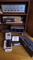 Overall view of Ross 8-track player, car stereo, adaptor box, tapes and case
