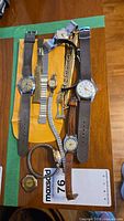 Overview of six wristwatches and loose bands on table