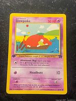 Front of Slowpoke 1st Edition Team Rocket card showing artwork, stats, set stamp, card number 67/82