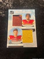 Front of card showing portraits of Jayden Daniels and Luke McCaffrey with red and yellow sweater patches