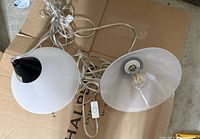 Two pendant lights on floor showing cords, inline switch and bulbs