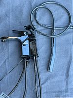 Two chrome Riobel sink faucets with braided lines and chrome handheld shower wand with hose on fabric background