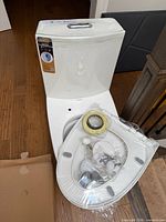 Front view of sealed one-piece toilet with packaged seat and hardware