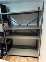 Fully assembled gray steel shelving unit with four shelves and cross braces