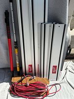 Full lot showing five Milwaukee guide rails, two telescopic poles and coiled red extension cord