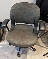 Front view of grey fabric rolling office chair showing seat, arms and caster base