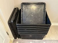 Stack of six black plastic totes with lids alongside