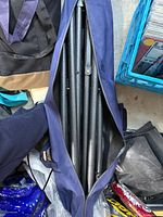 Disassembled black steel stand inside navy zip carry bag