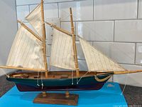 Port side view of full model sailboat showing sails, hull colors and stand