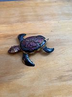 Top view of metal sea turtle showing cracked red shell and gold highlights