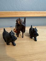 Front view of two cast iron Scottie dog figurines and wooden donkey spool holder
