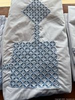 Folded tablecloth showing main blue geometric embroidery