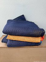 Stack of three moving blankets folded on bench