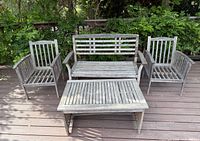 Full view of wooden outdoor patio set showing bench, two armchairs and coffee table on deck