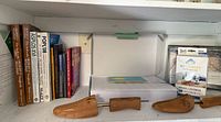 Shelf with books, two shoe stretchers, white storage box, boxed device