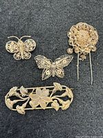 Front view of four sterling silver filigree brooches on dark background