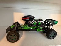 Left side view of green/black Adventure Force RC buggy with remote behind