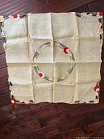 Full view of folded square tablecloth showing central wreath and corner appliqué