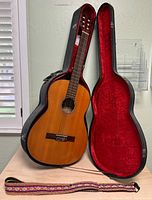 Classical guitar inside open hard case with strap visible