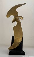 Front view of brass bird sculpture on black pedestal