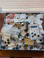 Overview of shallow box filled with vintage buttons, many on original cards