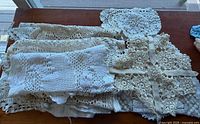 Stack of vintage crocheted doilies and lace linens on table